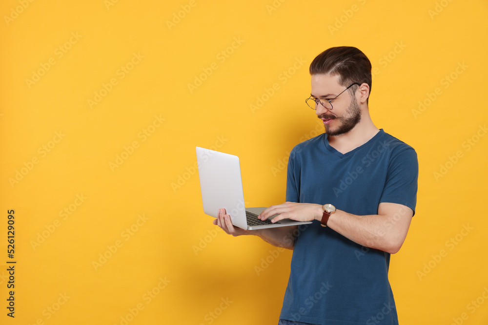 Happy man using laptop on orange background. Space for text Happy man using laptop on orange background. Space for text