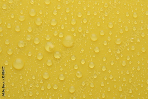 Water drops on yellow background, top view