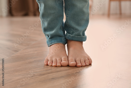 Little child walking barefoot at home, closeup. Floor heating concept