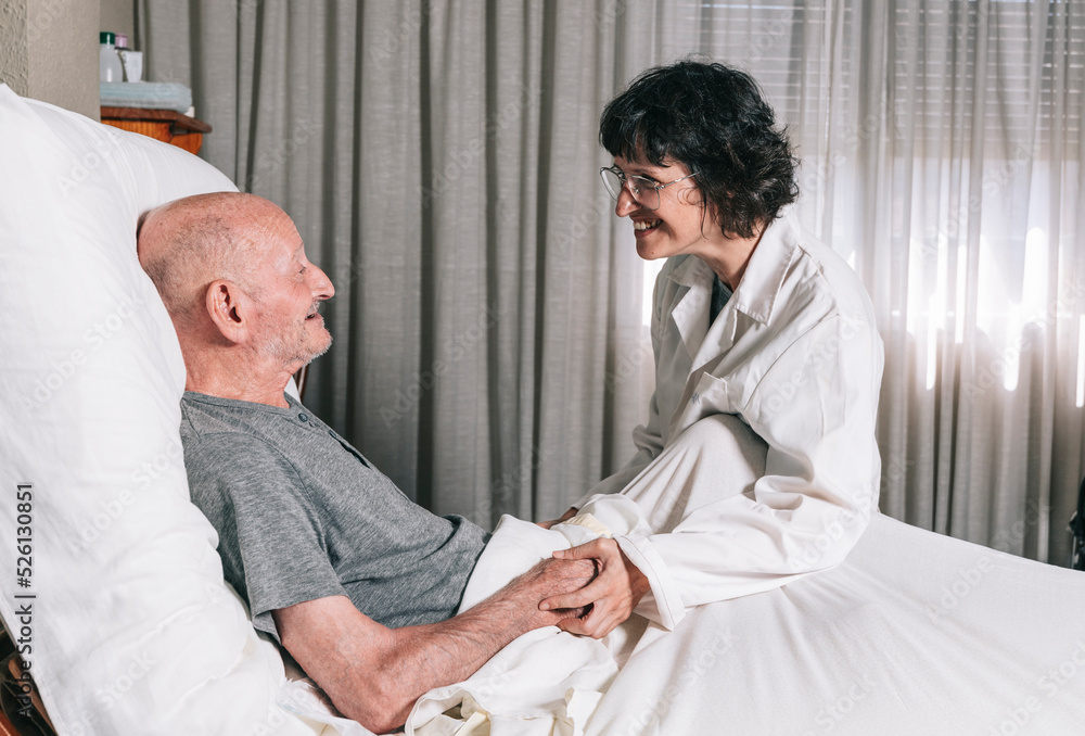Fototapeta premium nurse assisting a smiling old man lying on his bedroom bed