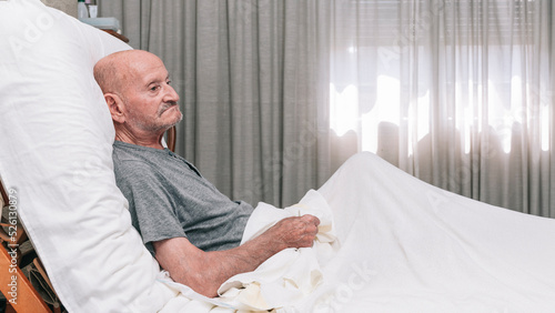 elderly man lying on a bed alone