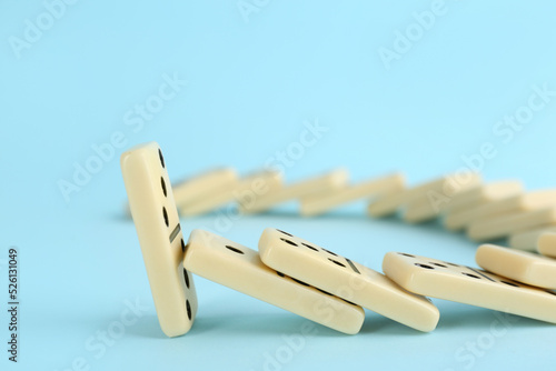 Fotografie White domino tiles falling on light blue background