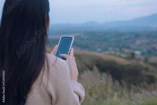 Woman is checking Bitcoin price chart on digital exchange on smartphone, cryptocurrency future price action prediction.