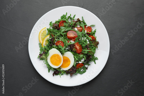 Wallpaper Mural Delicious salad with boiled egg, arugula and tomatoes on black table, top view Torontodigital.ca