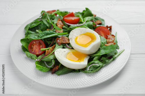 Delicious salad with boiled egg, bacon and tomatoes on white wooden table, closeup