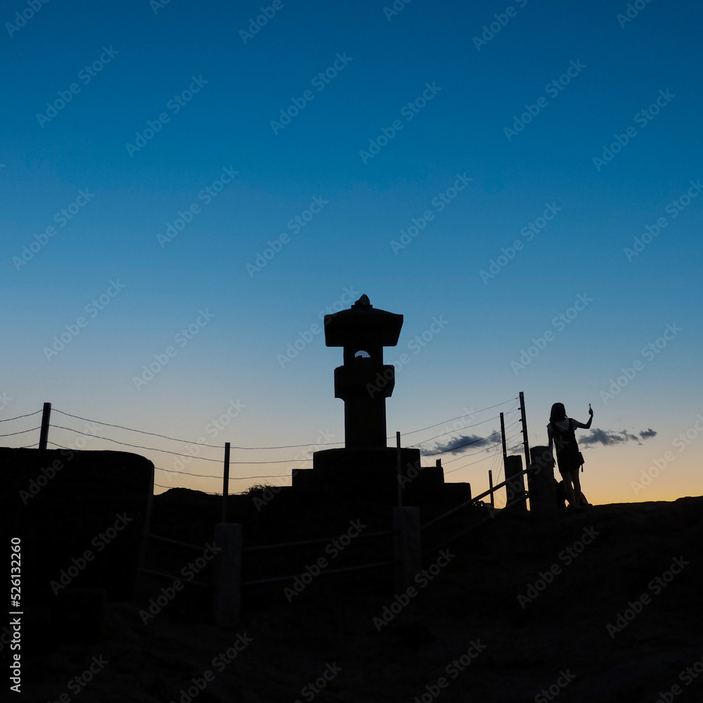 江ノ島の灯籠と海の景色を眺めるひとたち。シルエット。日没直後の風景。