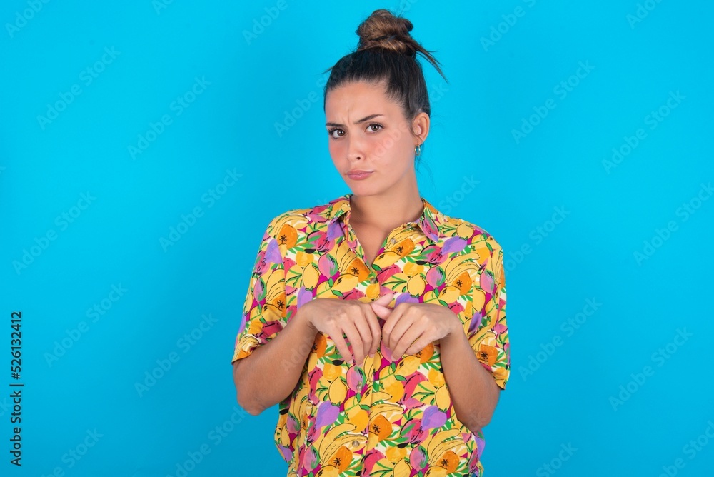 beautiful brunette woman wearing colourful shirt over blue background makes bunny paws and looks with innocent expression plays with her little kid beautiful brunette woman wearing colourful shirt over blue background makes bunny paws and looks with innocent expression plays with her little kid