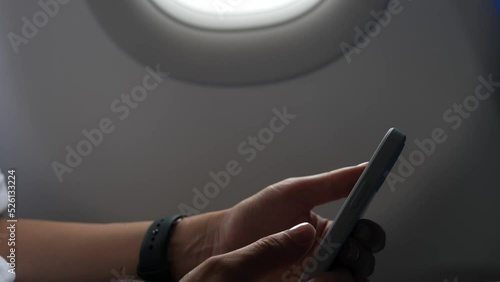 Female passenger on the plane is viewing information on a mobile phone.