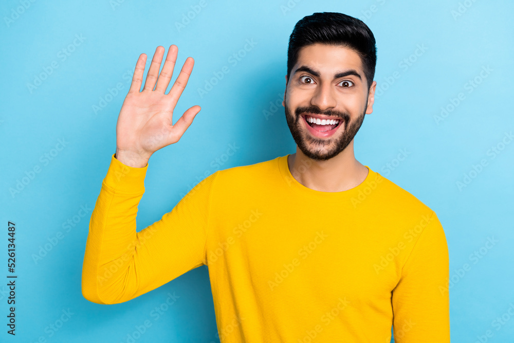 Photo of excited funny young guy dressed yellow pullover smiling waving arm palm isolated blue color background Photo of excited funny young guy dressed yellow pullover smiling waving arm palm isolated blue color background