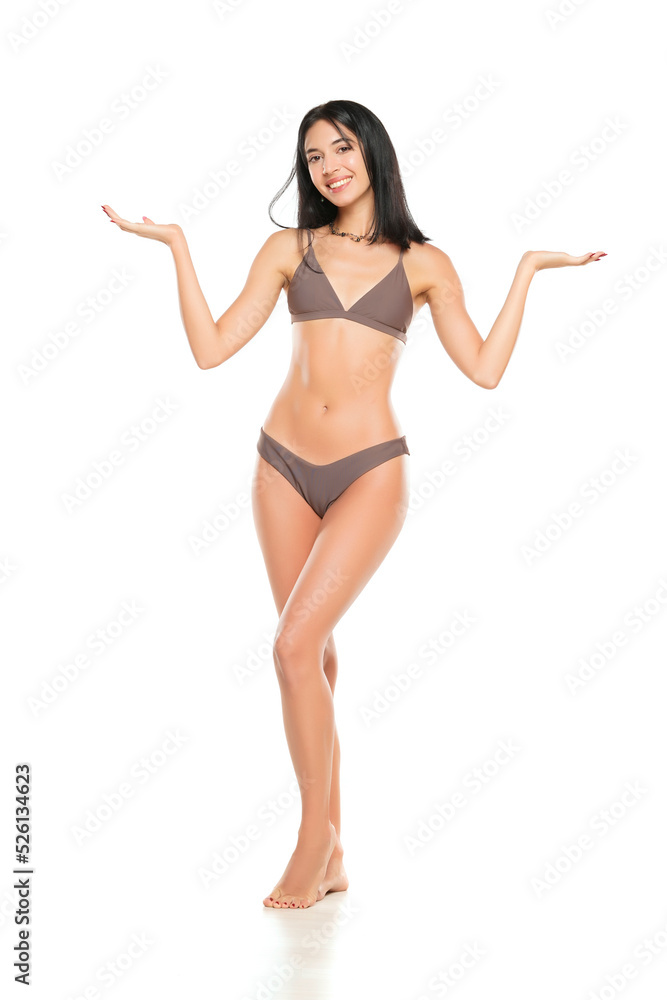 Young smiling brunette woman in bikini swimsuit advertising imaginary object on her hand on a white background. Young smiling brunette woman in bikini swimsuit advertising imaginary object on her hand on a white background.