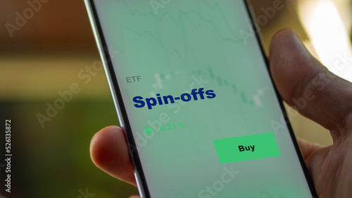 An investor's analyzing the fund etf on screen. A phone shows the ETF's prices spin-offs