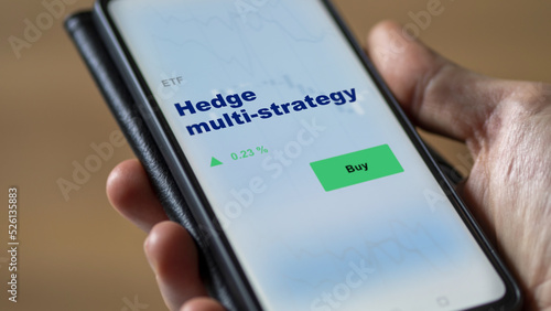 An investor's analyzing the fund etf on screen. A phone shows the ETF's prices hedge multi-strategy