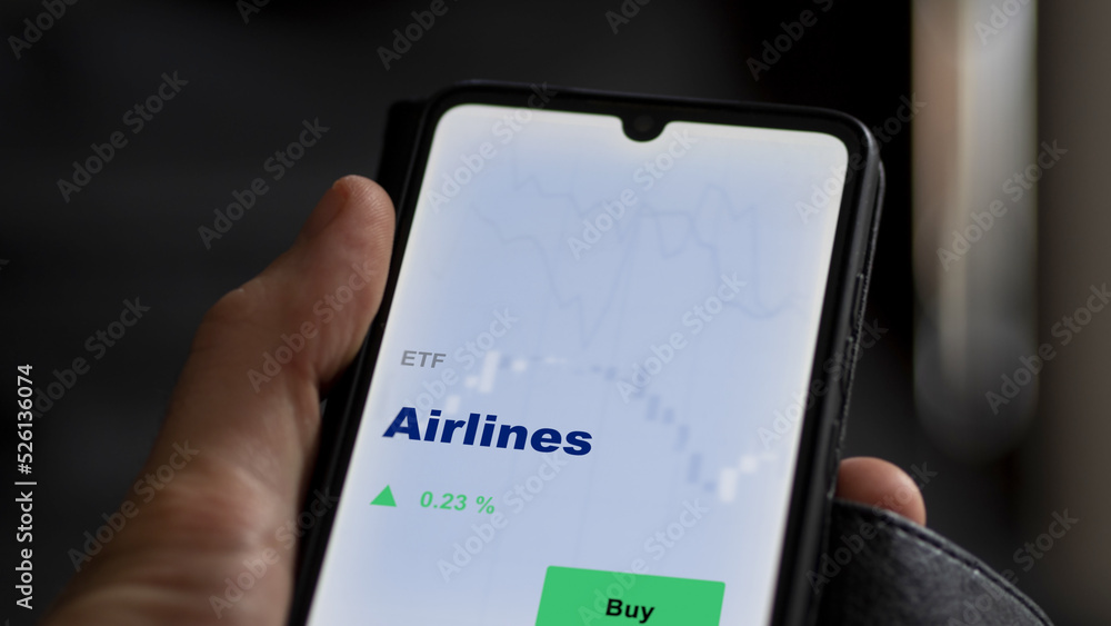 An investor's analyzing the etf fund on screen. A phone shows the ETF's prices airlines An investor's analyzing the etf fund on screen. A phone shows the ETF's prices airlines