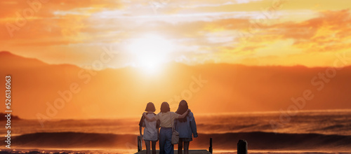 three women stand on the beach pier hugging back view sunset sky background. happy family and travel vacation concept. © Njay