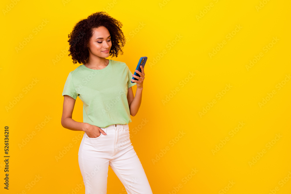 Photo of sweet shiny girl dressed green t-shirt typing modern device empty space isolated yellow color background Photo of sweet shiny girl dressed green t-shirt typing modern device empty space isolated yellow color background