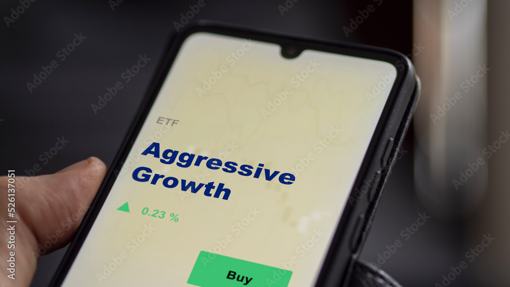 An investor's analyzing the Aggressive Growth etf fund on screen. A phone shows the ETF's prices aggressive growth stocks to invest An investor's analyzing the Aggressive Growth etf fund on screen. A phone shows the ETF's prices aggressive growth stocks to invest
