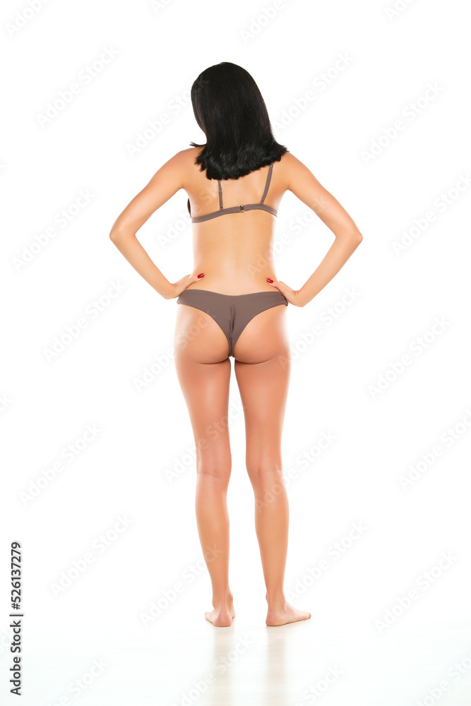 Back view of a young brunette woman in bikini swimsuit posing on a white background. Back view of a young brunette woman in bikini swimsuit posing on a white background.