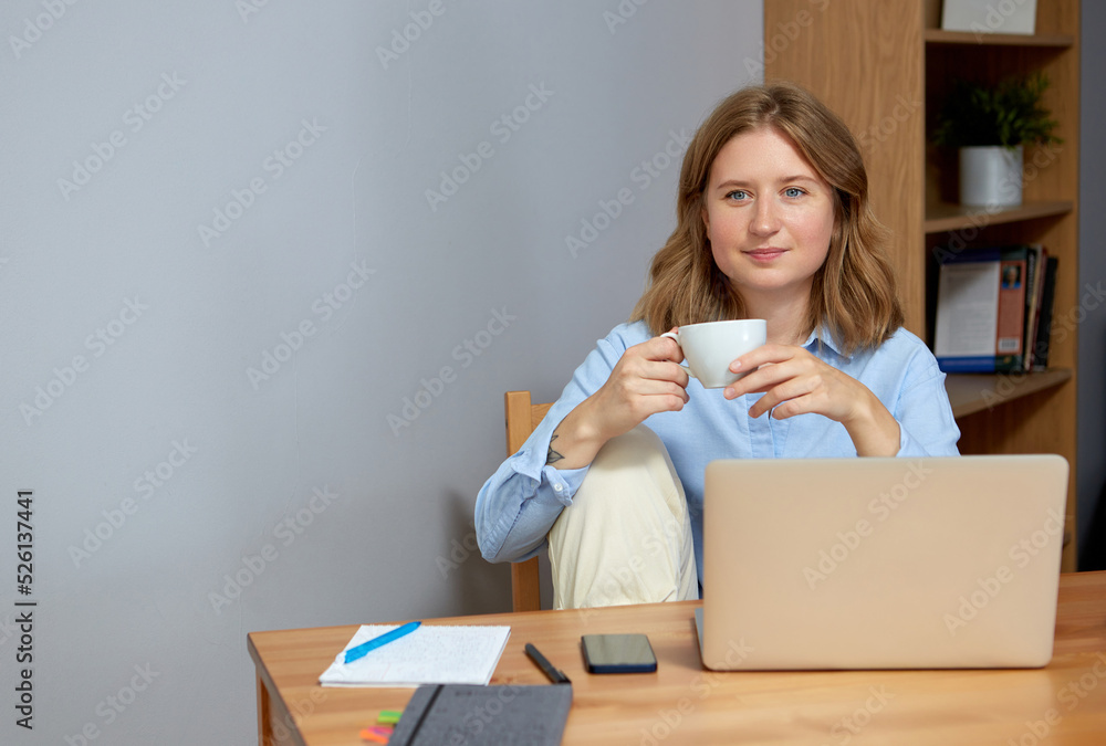 Beautiful young woman working on laptop while sitting at the living room, drinking coffee. Beautiful young woman working on laptop while sitting at the living room, drinking coffee.
