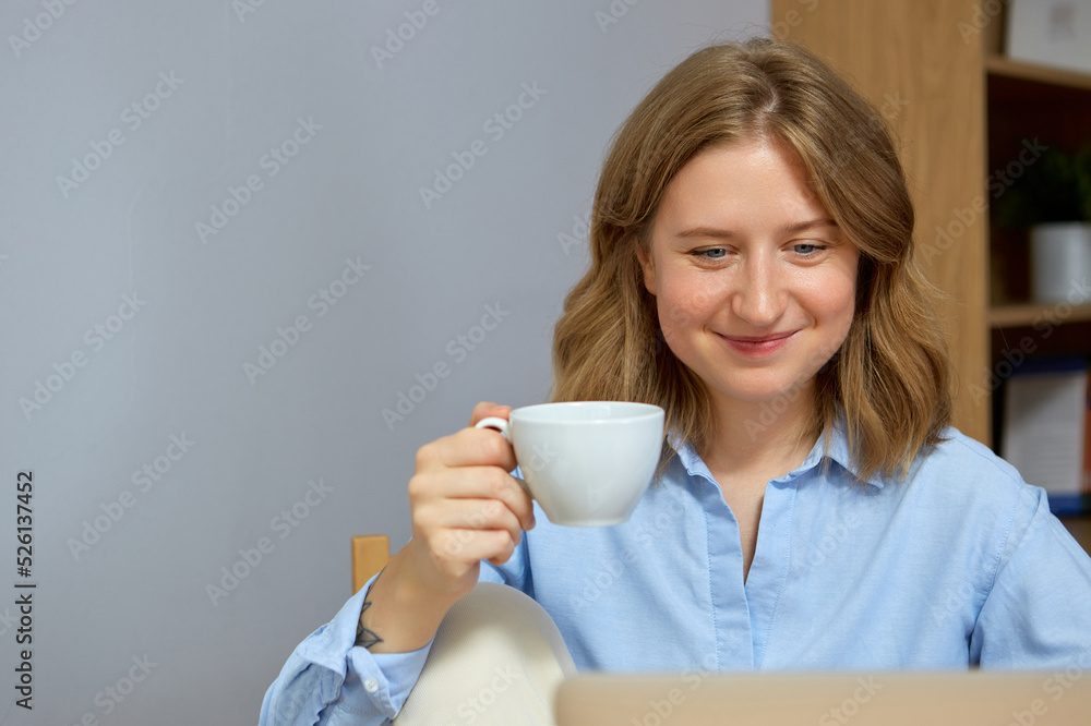 Close up portreit of young woman working on laptop while sitting at the living room, drinking coffee. Close up portreit of young woman working on laptop while sitting at the living room, drinking coffee.