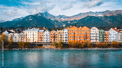 Picturesque view of the colorful houses along the Inn River in Innsbruck, Austria, with the Alps in the background.