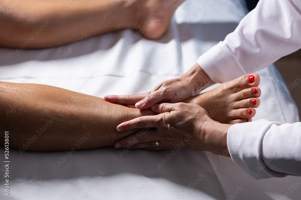 Um profissional fazendo massagem terapêutica no joelho do paciente que ...