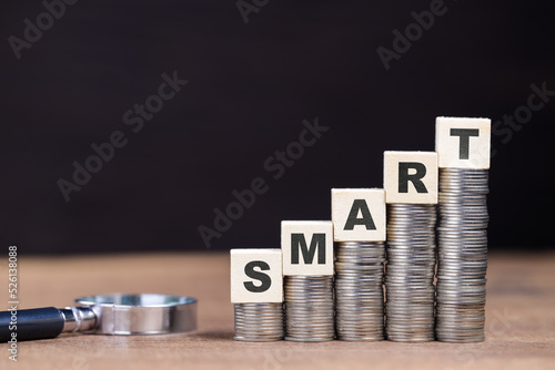 Growth money stacks with text and magnifying glass, smart idea to make money, spend wisely for more savings, smart investment concept photo