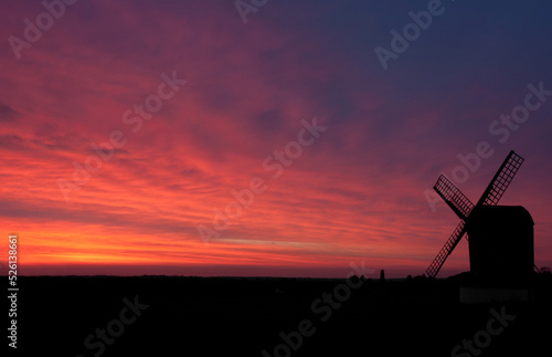 A windmill in Hertfordshire silhouetted by the pink-purple setting sun. 