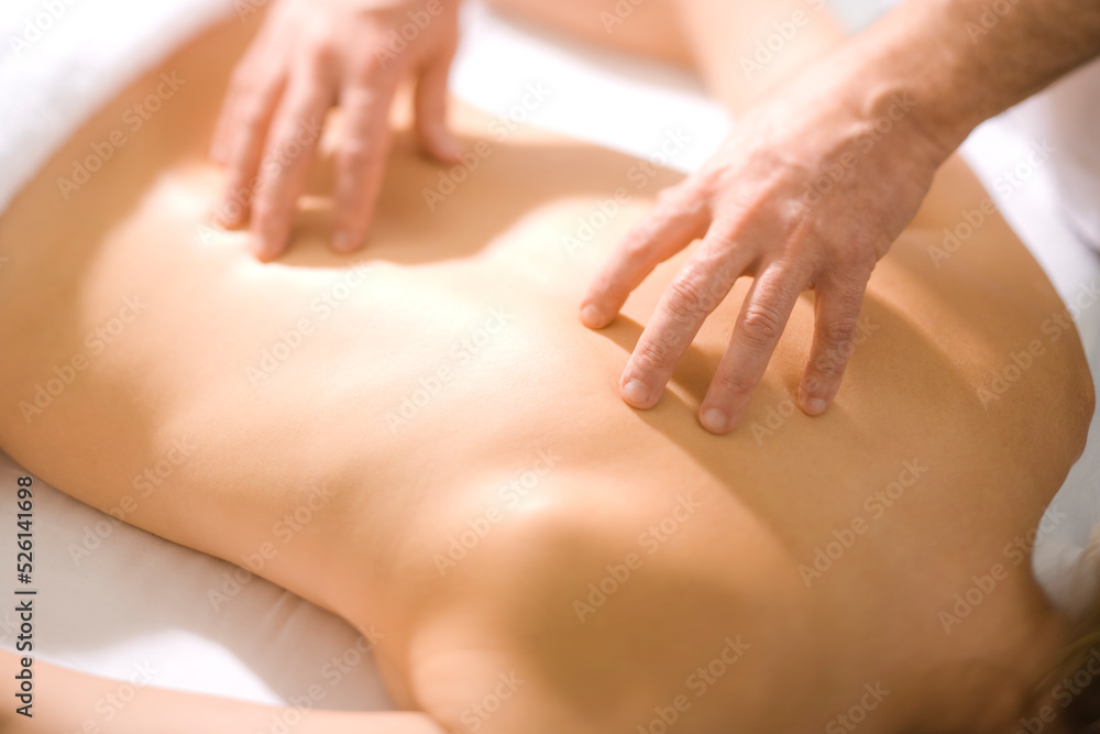 Fototapeta premium A Massage Therapist Practitioner evaluates a patients back strain with therapeutic touch.