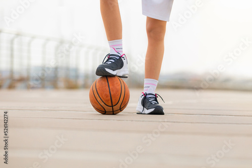 Close-up detail of a woman's sneakers stepping on a basketball. Shallow depth of field with copyspace © Valoa Studio