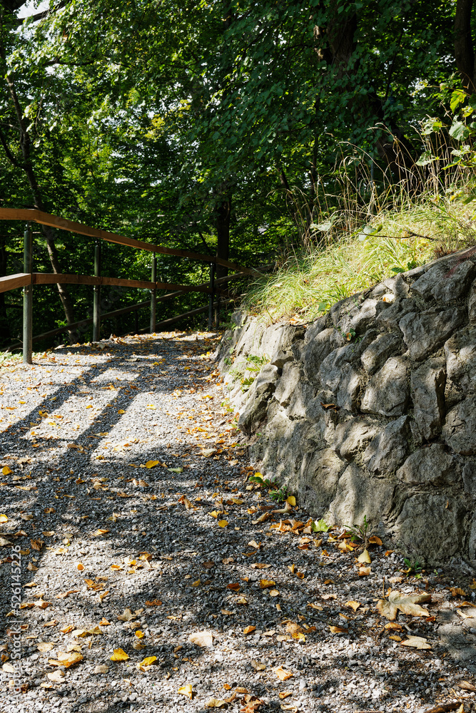 Footpath with gravel leads to a hill, between railings and a retaining ...