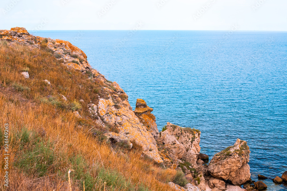 Sea mountain landscape. Blue sea and rocks with dry grass. Travel and tourism