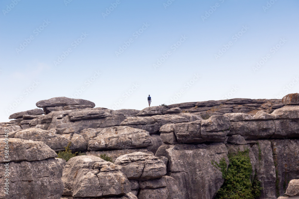 man walking alone in the mountain, panoramic with blue sky and clouds, (El Torcal, Antequera)