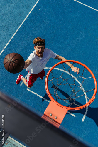 top view of redhead excited man throwing ball into basketball hoop © LIGHTFIELD STUDIOS
