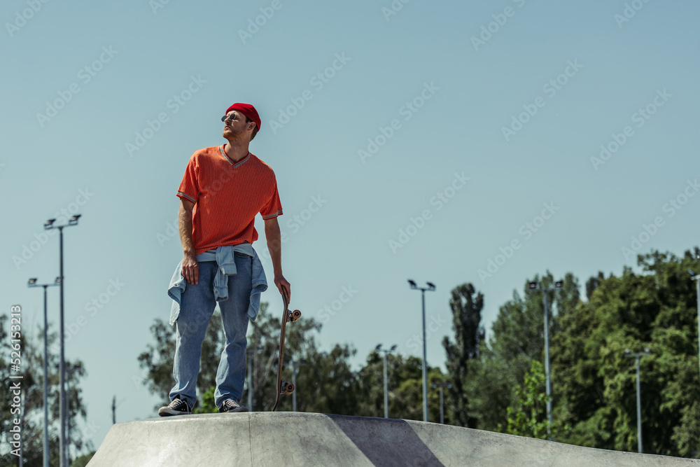 full length of stylish skater looking away while standing on ramp in skate park full length of stylish skater looking away while standing on ramp in skate park