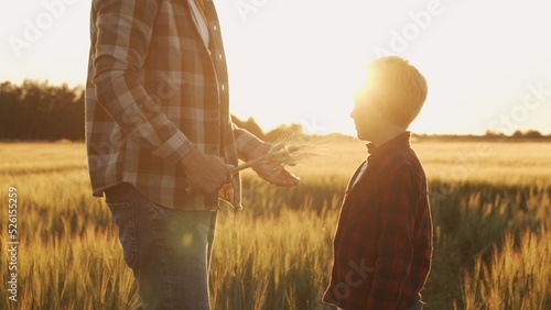 Farmer and his son in front of a sunset agricultural landscape. Man and a boy in a countryside field. Fatherhood, country life, farming and country lifestyle.