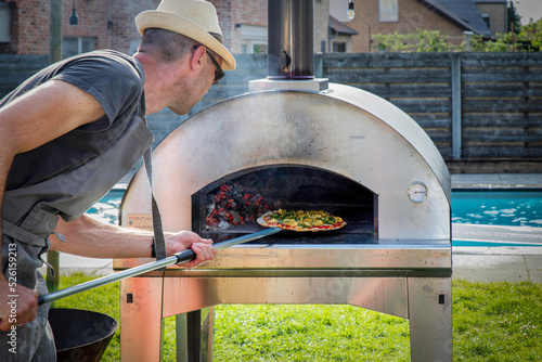 a man put a home made pizza in the wooden oven