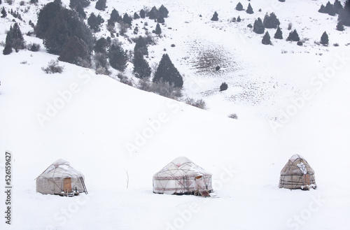Yurts in winter. National ancient house of the peoples of Kyrgyzstan and Asian countries. national housing. Yurts against the backdrop of snow and highlands. Yurt camp for tourists. © Vera