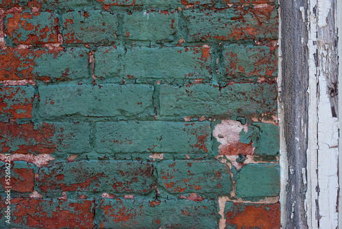 Old vintage red brick and peeled paint wall masonry exterior.