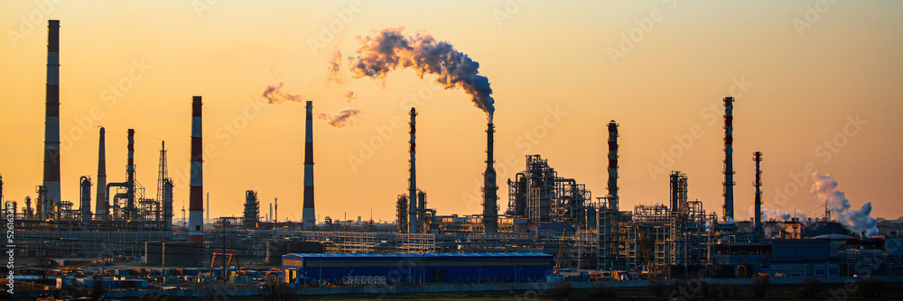 Obraz premium Working oil refinery. Smoke from the factory chimney. Ecological pollution. Air emissions polluting the city. Industrial waste is hazardous to health. Large factory in smog, Production in operation.