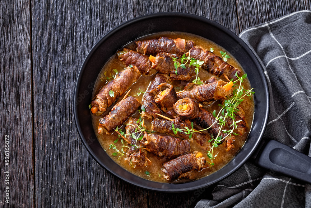 german beef rouladen in thick gravy on pan