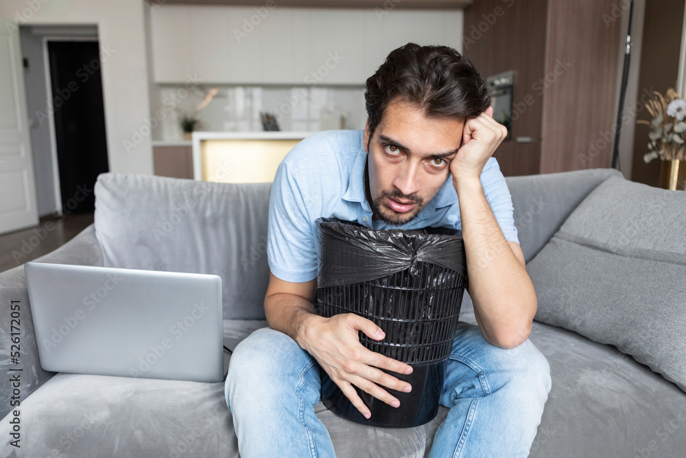 Young man vomiting in rubbish bin after exhausting busy work day Young man vomiting in rubbish bin after exhausting busy work day