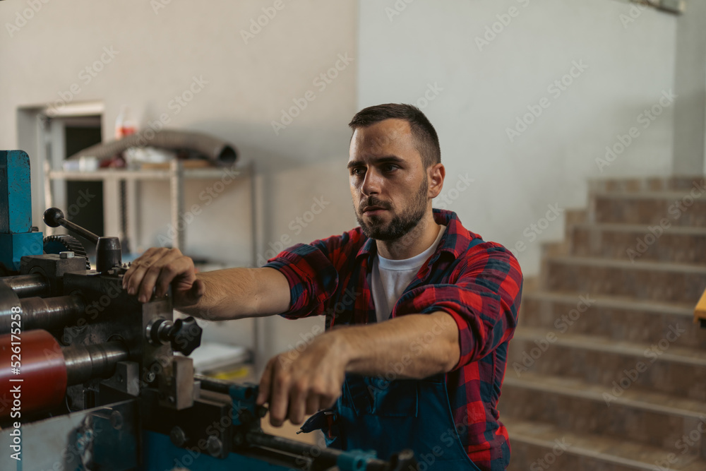 The young craftsman works on a large printing machine in the company. The young craftsman works on a large printing machine in the company.
