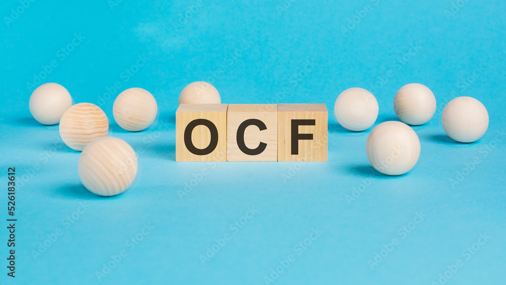 business concept. on the blue table wooden balls and wooden cubes with the inscription - OCF - Operating Cash Flow