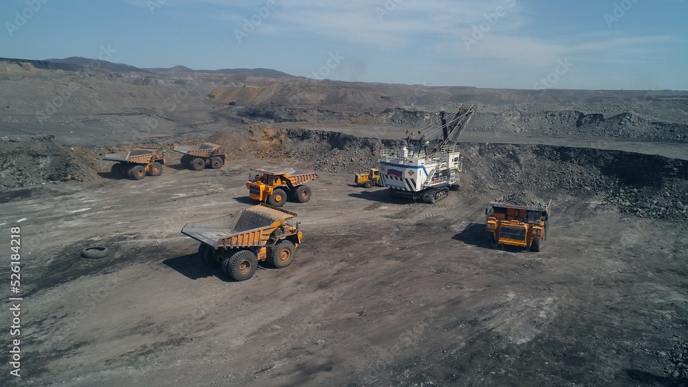 Loading queue from giant dump trucks to mining excavator. Open pit coal mining Loading queue from giant dump trucks to mining excavator. Open pit coal mining