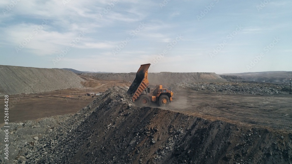Multi-ton dump truck folds its body and leaves after unloading waste rock. Element of coal mining process. Aerial view