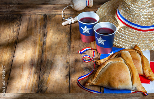 Chilean independence day concept. fiestas patrias. Tipical baked empanadas, wine or chicha, fat and play emboque. Decoration for 18 september party day, wooden background, top view photo