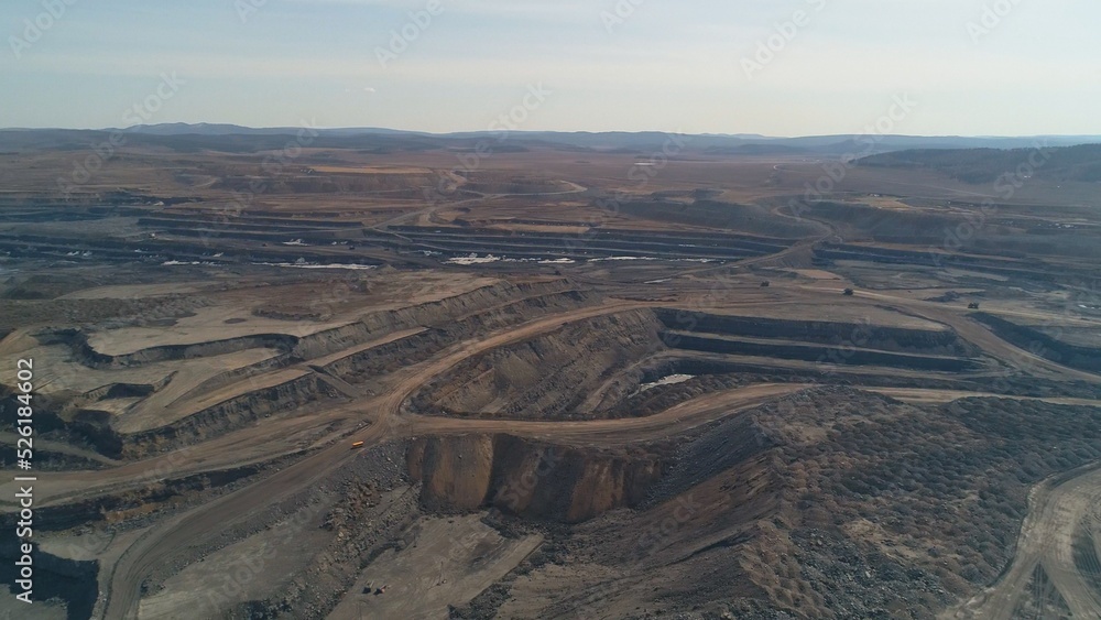 Deep quarry with working equipment. Mining machines. Excavator, dump truck, loader. Copter view