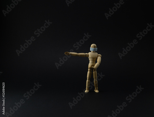 Wooden mannequin with protective surgical mask in black background
