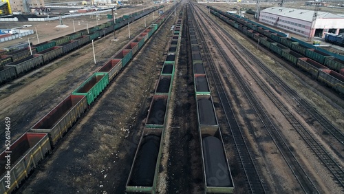 Locomotives carrying trains with coal are waiting for permission to start. Black smoke from the chimney of a diesel locomotive pollutes the atmosphere, emits carbon dioxide. Aerial view