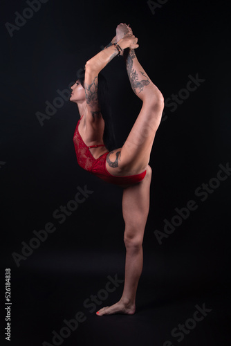 Photo of gymnast girl with tattoo stretching in red lingerie